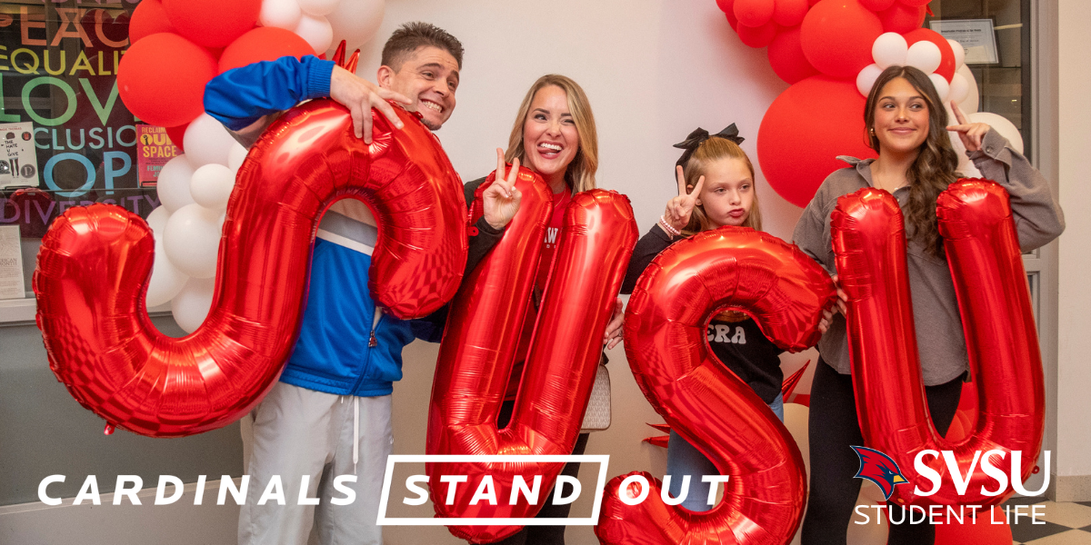 A family standing with inflatable SVSU letters looking past the camera smiling and making peace signs with their hands.